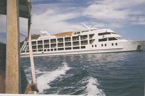 white multi-deck ferry ship photographed from a small boat at sea