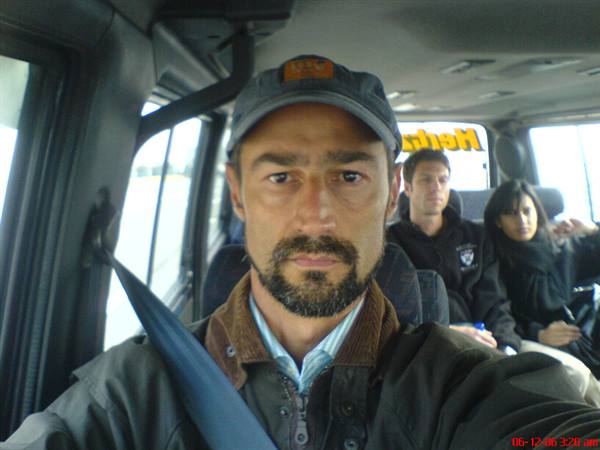 Man in cap wearing seatbelt driving a van, passengers seated behind him