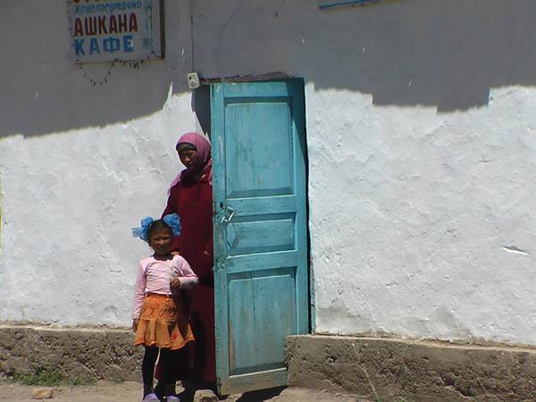 Veiled woman and little girl by blue door of a café