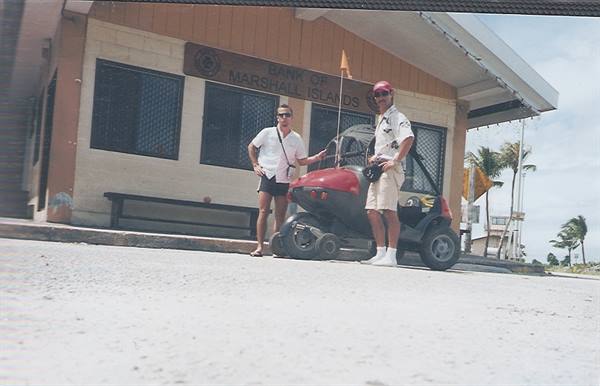 Two tourists beside a golf cart in front of the Bank of Marshall Islands