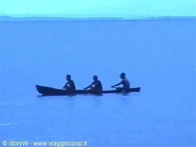 Three fishermen paddle a dark canoe across the blue water