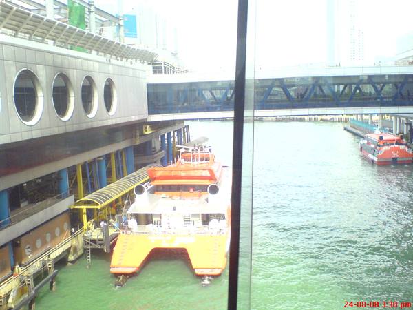 Orange ferry docked at the pier, glass walkway above green water