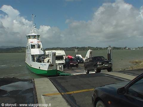 Green and white ferry loading cars onto the ramp at the harbor