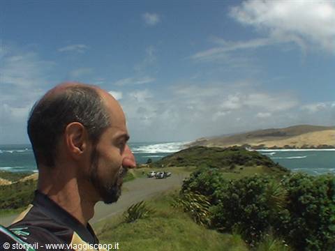 Bearded man gazes at the ocean from green cliffs at Cape Reinga