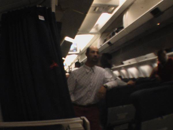 Man in light shirt standing in an airplane cabin aisle