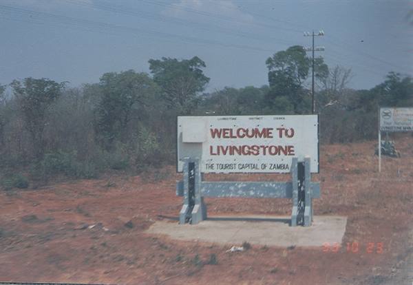 Welcome to Livingstone concrete roadside sign beside dusty road among dry trees