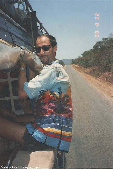 Traveler in tropical shirt and sunglasses on a van along the paved road