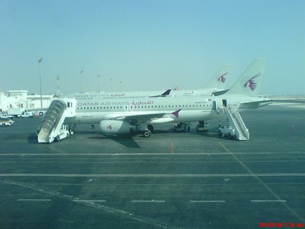 Qatar Airways jets parked on the apron with boarding stairs down