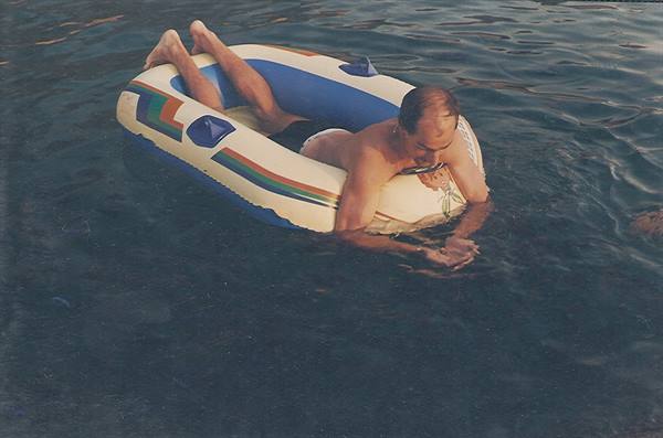 Man lying on colorful inflatable raft floats on the sea wearing snorkel mask