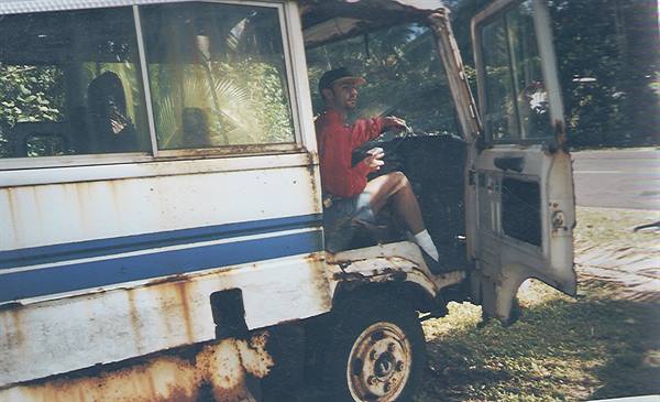 Young man in red cap driving a rusty old minibus