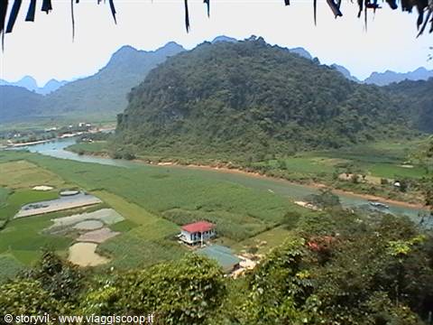 River winding through green limestone karst hills, farmland and a red-roofed house