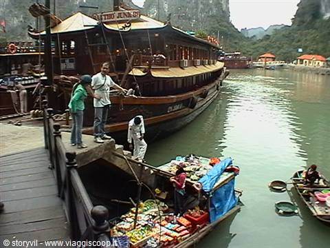 Wooden junk moored at Ha Long, women sell fruit from small boats