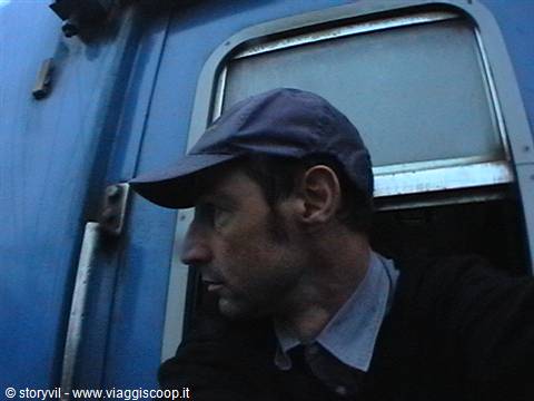 Man in blue cap beside the metal window frame of a blue train carriage