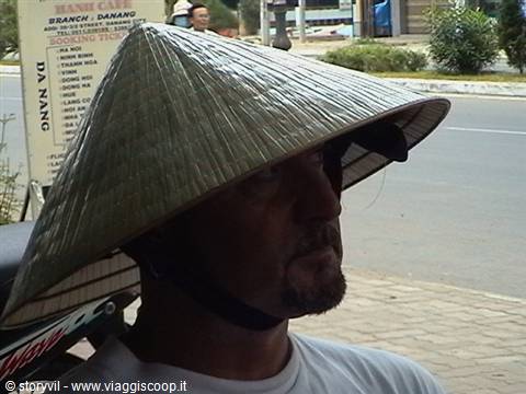 Man wearing conical straw hat on his face, urban street with sign behind