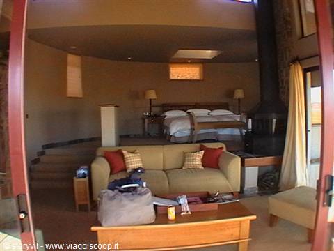 Lodge suite with sofa, fireplace and elevated bed in safari camp