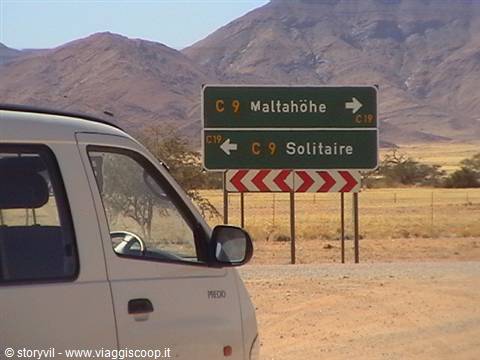 Green road sign points to Maltahöhe and Solitaire among arid mountains