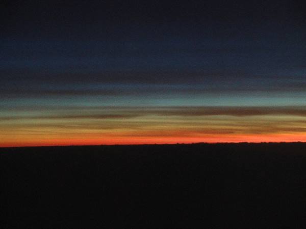 Orange glow on dark horizon seen from an airplane window