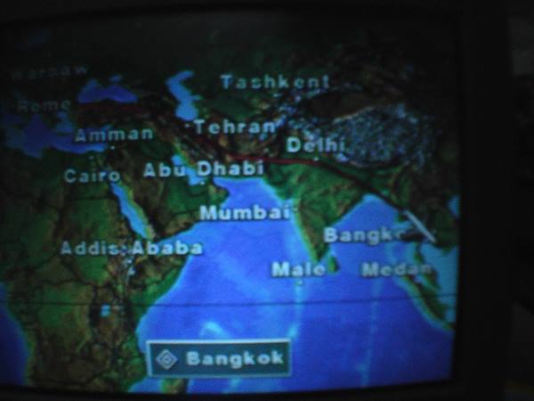 Flight map on screen: route toward Bangkok, glowing over blue background
