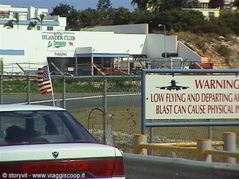 Airport warning sign about low flying jets, car and American flag by Islander Club
