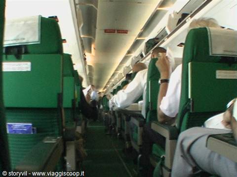 Airplane cabin with green seats and passengers in white shirts