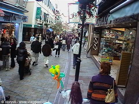 Child holding a flower balloon among pedestrians in a busy shopping street