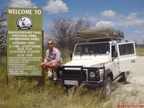 Tourist beside a Land Rover at the Makgadikgadi Pans National Park entrance sign