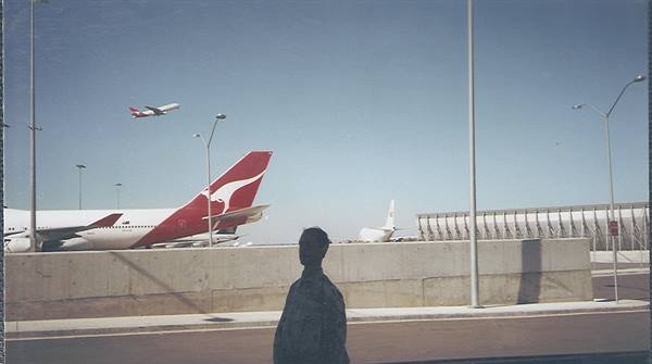 Qantas kangaroo-tailed plane at the airport, silhouetted man in foreground