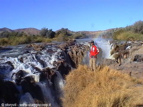 Epupa Falls, man in red jacket standing on rocks by the cascading river