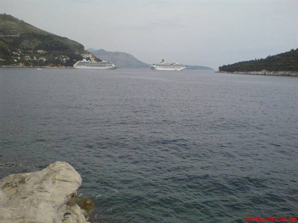 Two cruise ships anchored in the bay off Dubrovnik, rocks in foreground