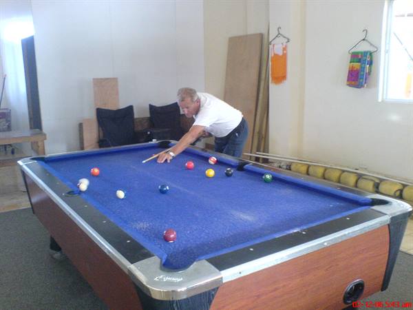Man aiming a shot on a blue-cloth pool table in an indoor room