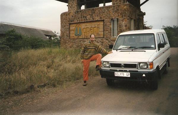 Man leaning on white Toyota van by Orpen stone gate entrance