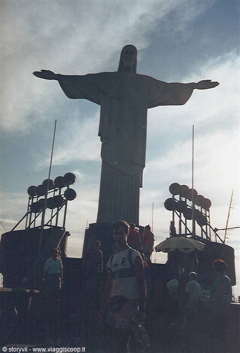 Tourists beneath Christ the Redeemer in Rio de Janeiro, backlit with floodlights