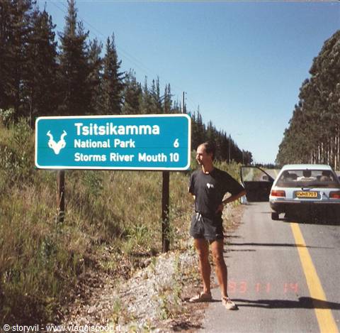 Tourist beside the Tsitsikamma National Park sign, car parked along the road