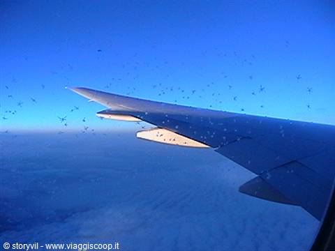 Airplane wing with frost on the window above the clouds