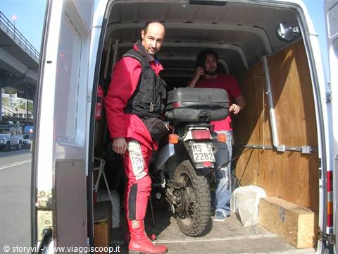 Two men loading a dirt bike into the van
