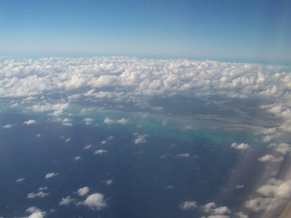 White clouds over the blue ocean seen from the airplane window