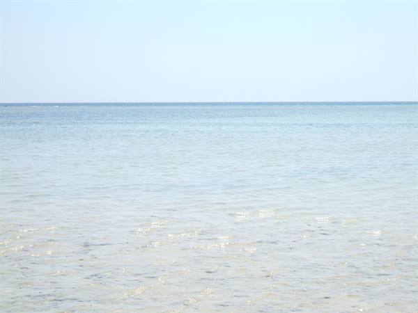 Clear shallow water meets the blue sky at the horizon