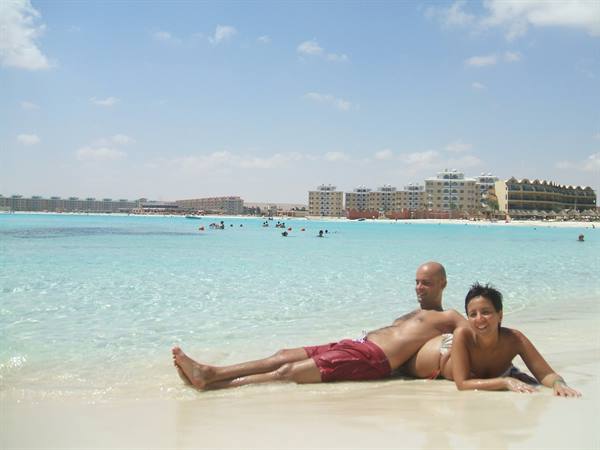 Couple lying on wet sand in front of turquoise water and hotels