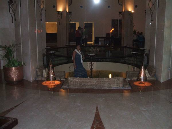 Woman in blue dress near sofas and lanterns in marble hotel lobby