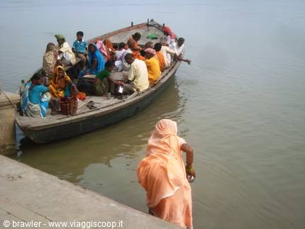 Wooden boat full of passengers on the Ganges, woman in orange sari crouching