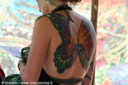 Woman with colorful butterfly tattoo on her bare back at outdoor festival