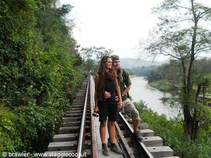 Couple walking on the Krasae viaduct railway tracks beside the river