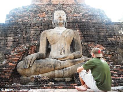 Tourist sitting before a large brick Buddha statue, Sukhothai