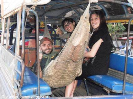 Three young travelers in a tuk-tuk, one resting in a hammock