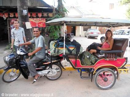 Driver and tourist on a red tuk-tuk loaded with backpacks on the street