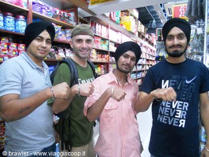 Four men wearing turbans showing their bracelets together in a supermarket