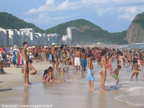 Crowd of bathers on Copacabana sand, skyscrapers and mountains in background