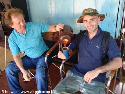 Man pouring mate from thermos into blue cup, sitting on folding chairs