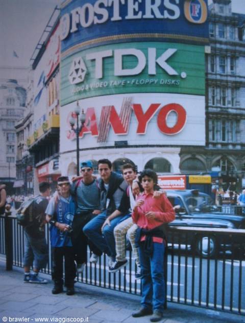 Group of young friends leaning on railings beneath Piccadilly Circus advertising billboards, London