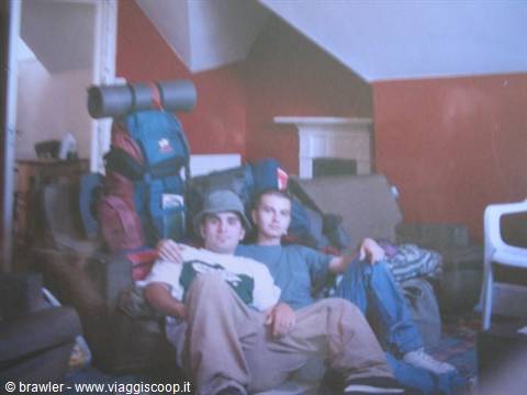 Two young backpackers with camping backpacks sitting on a sofa in a hostel